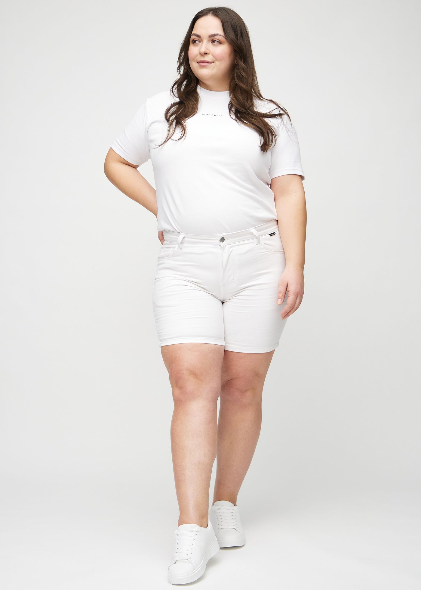 Fuldt billede af en plus-size model i hvide skinny short shorts.