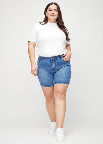 Fuldt billede af en plus-size model i denim skinny short shorts.