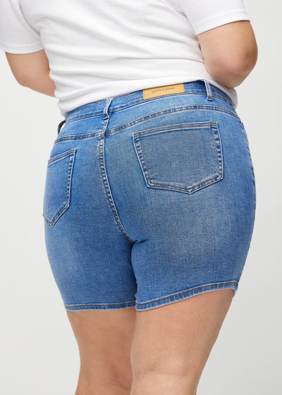 Denim skinny short shorts set bagfra tæt på en plus-size model for at vise detaljer.