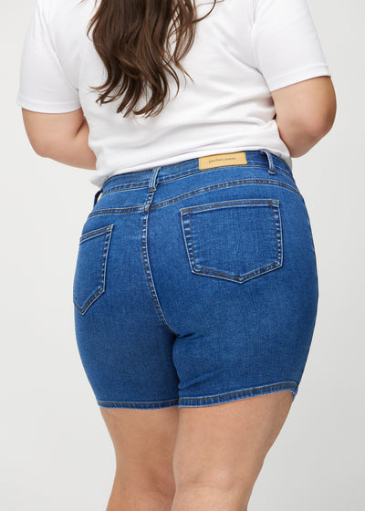 Mørk denim skinny short shorts set bagfra tæt på en plus-size model for at vise detaljer.