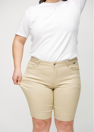 Plus-size model strækker shortsene ved låret for at vise stretch.