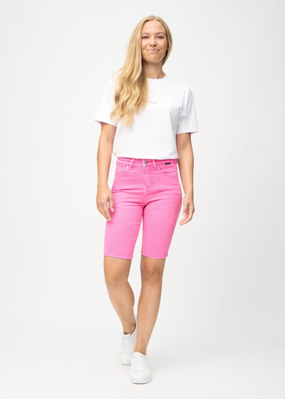 Fuldt billede af model i lyserøde skinny middle shorts.