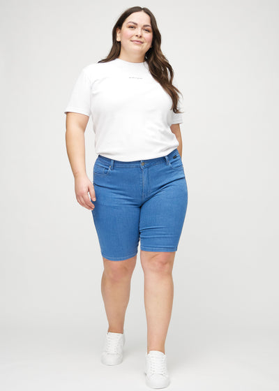 Fuldt billede af en plus-size model i blå skinny middle shorts.