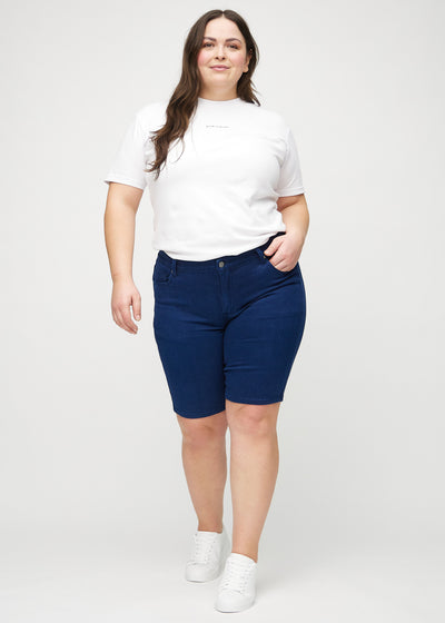 Fuldt billede af en plus-size model i mørkeblå skinny middle shorts.