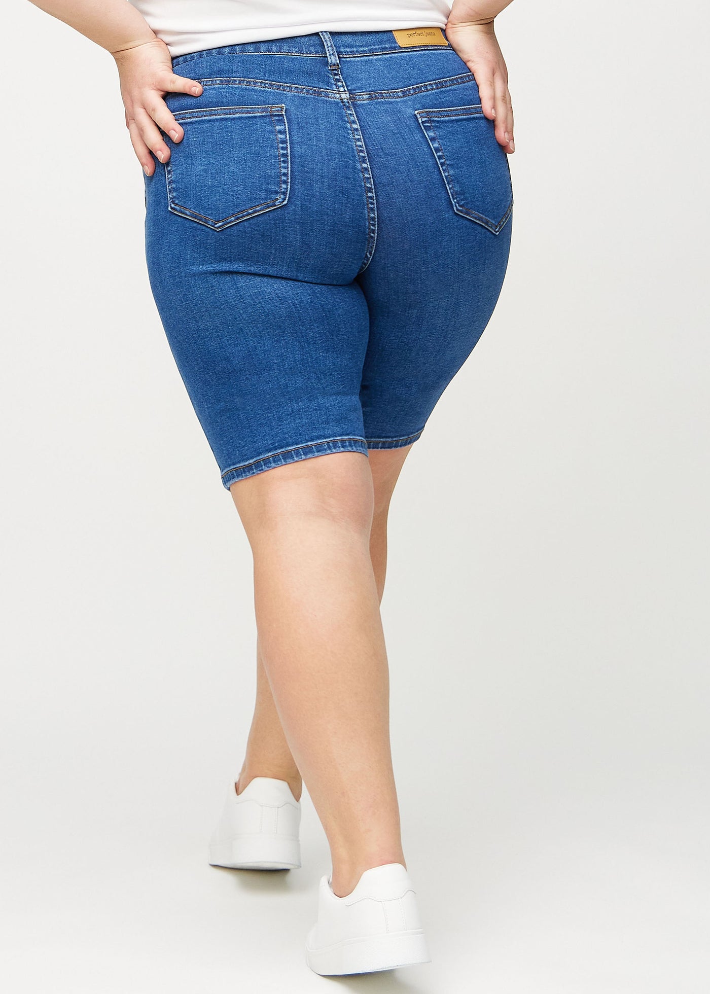 Mørk denim skinny middle shorts set bagfra på en plus-size model, så man kan se hele produktet.