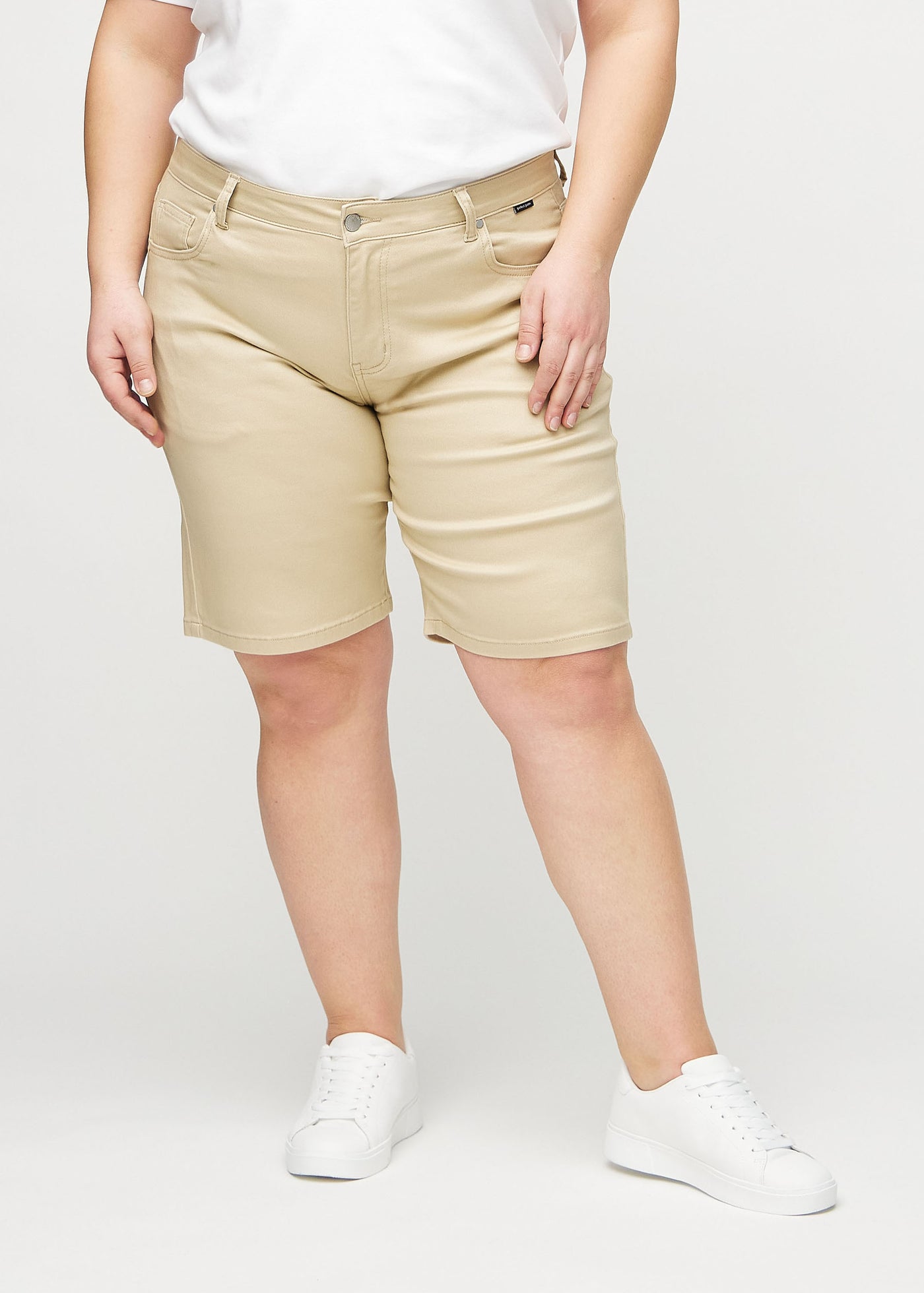 Beige regular middle shorts, modelnavn Gazelles, som går lige ned langs benet og slutter lige over knæet på en plus-size model, set forfra.