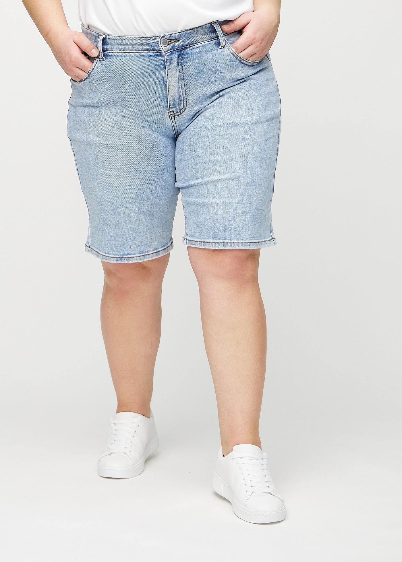 Lys denim regular middle ultra high rise shorts, modelnavn Waves, som går lige ned langs benet og sidder højt i taljen på en plus-size model, set forfra.