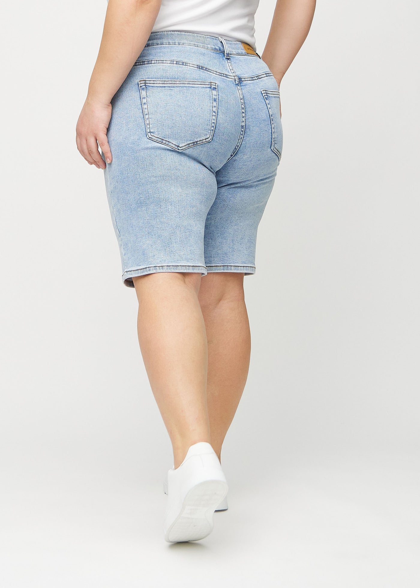 Lys denim regular middle ultra high rise shorts set bagfra på en plus-size model, så man kan se hele produktet.