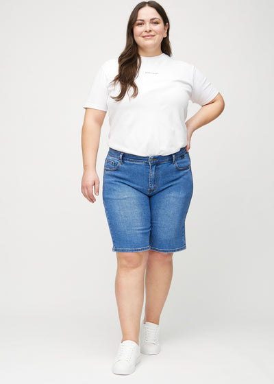 Fuldt billede af en plus-size model i denim regular middle ultra high rise shorts.