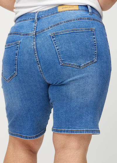 Denim regular middle ultra high rise shorts set bagfra tæt på en plus-size model for at vise detaljer.