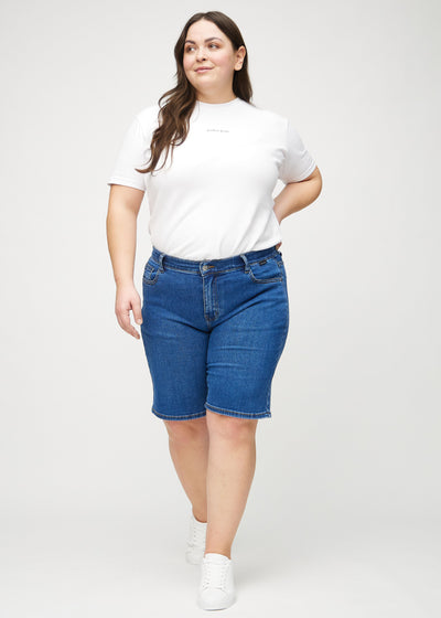 Fuldt billede af en plus-size model i mørk denim regular middle ultra high rise shorts.