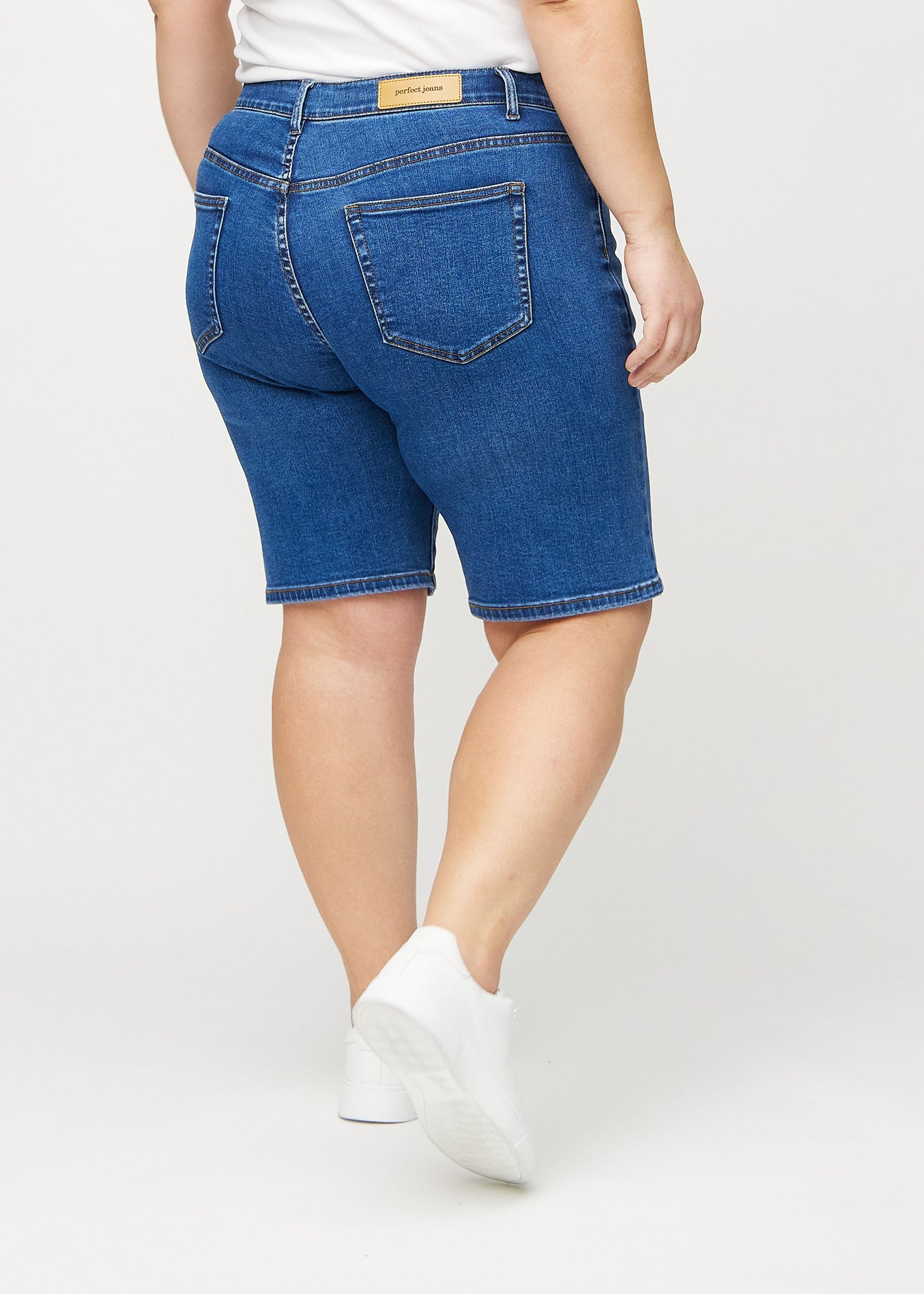 Mørk denim regular middle ultra high rise shorts set bagfra på en plus-size model, så man kan se hele produktet.