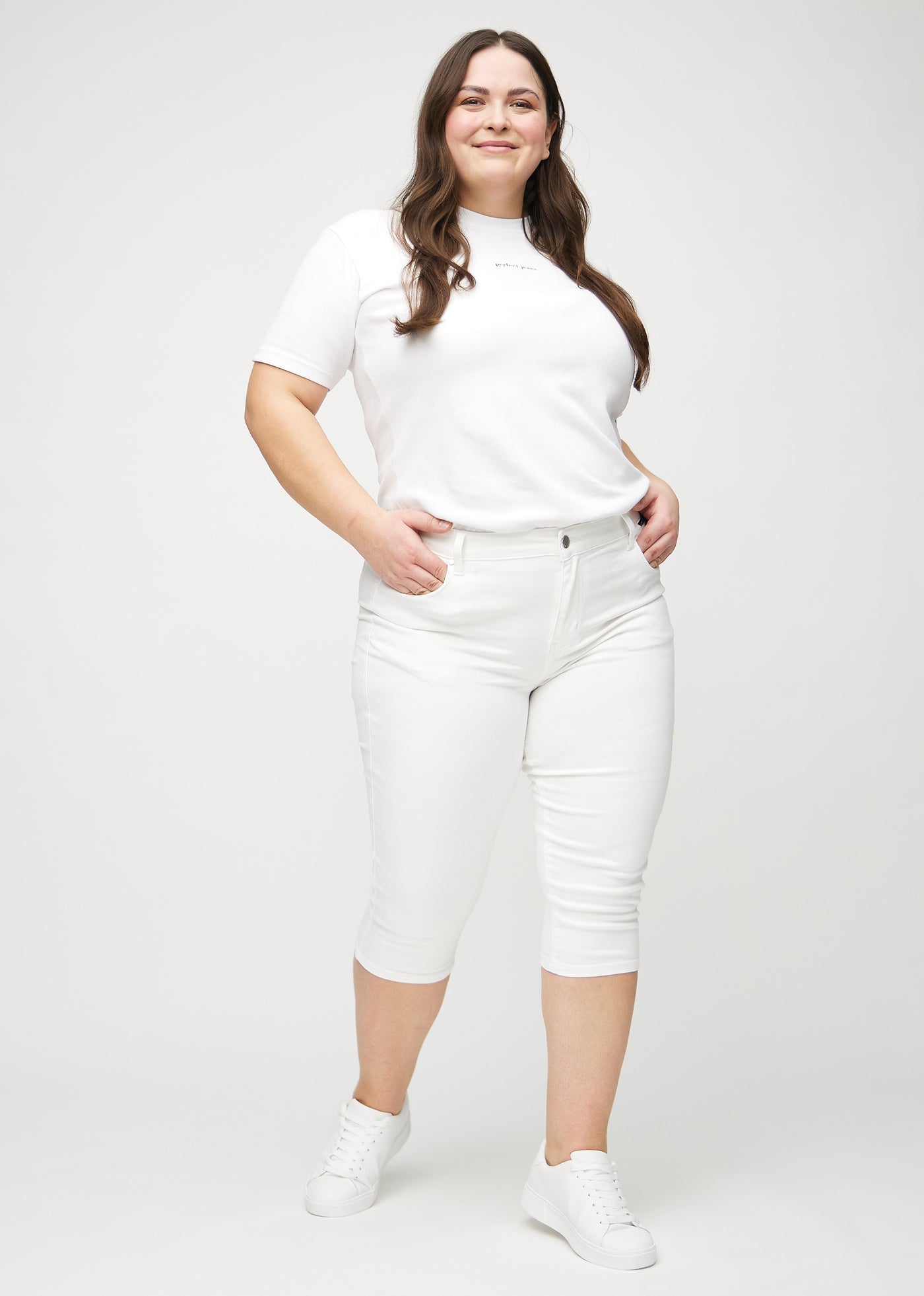 Fuldt billede af en plus-size model i hvide skinny capris.