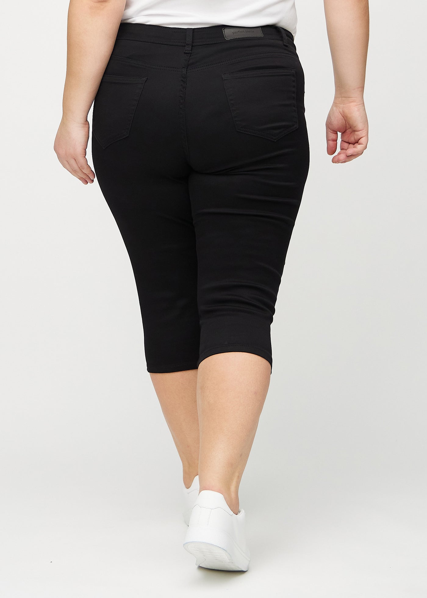 Sorte skinny capris set bagfra på en plus-size model, så man kan se hele produktet.