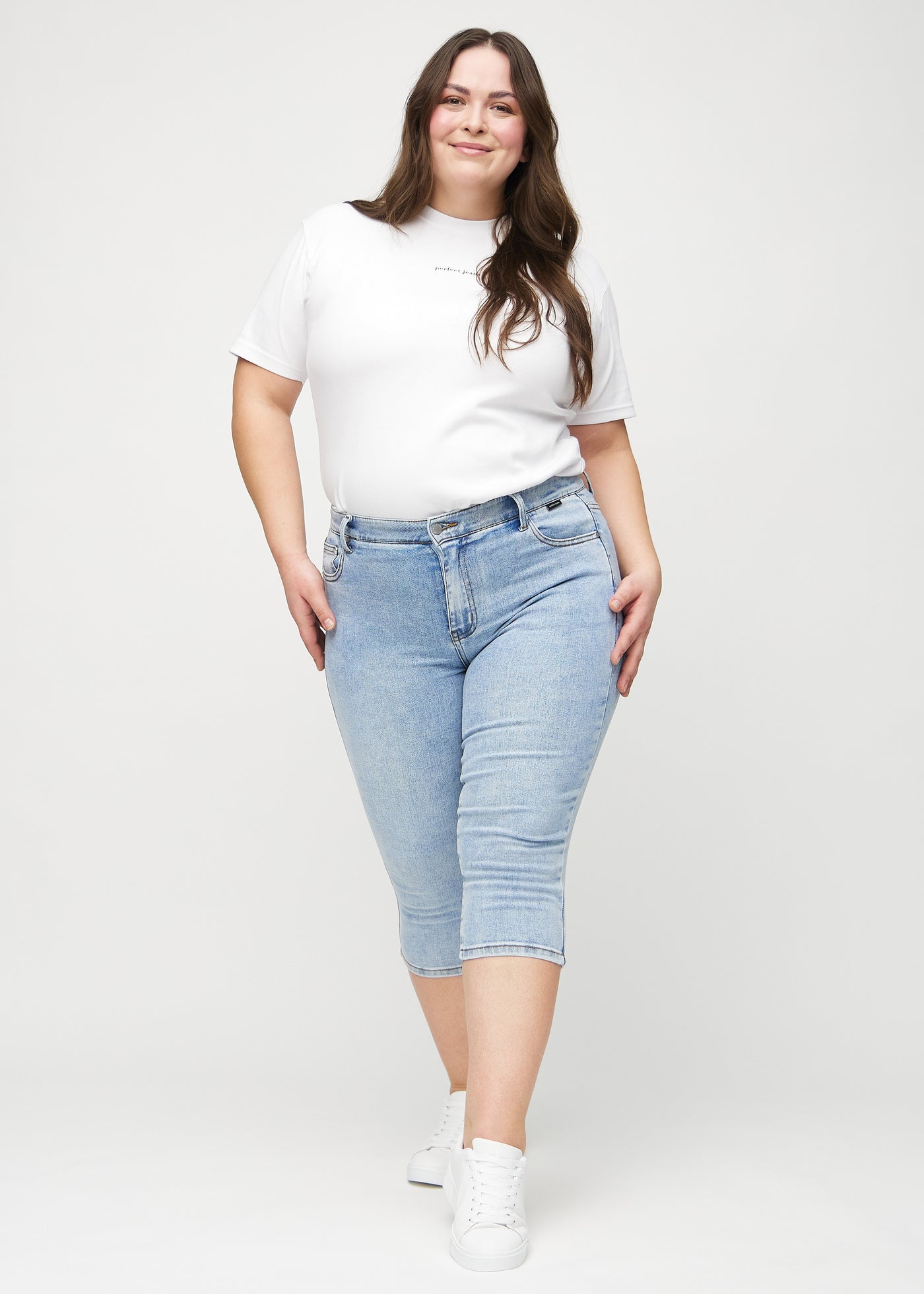 Fuldt billede af en plus-size model i lys denim skinny capris.