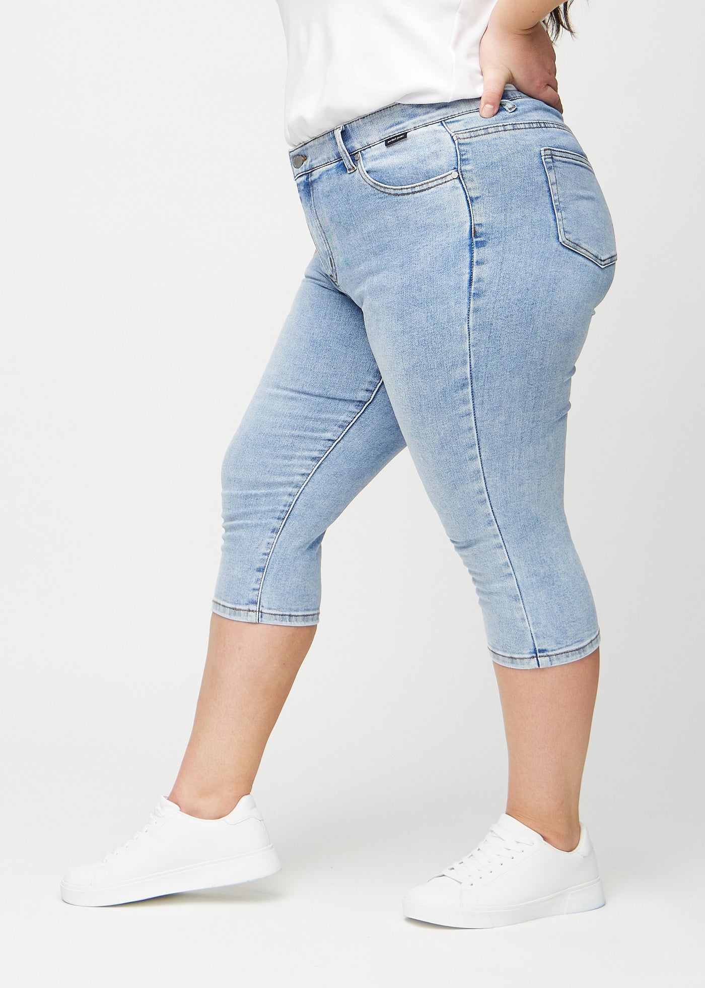 Lys denim skinny capris set fra siden på en plus-size model.