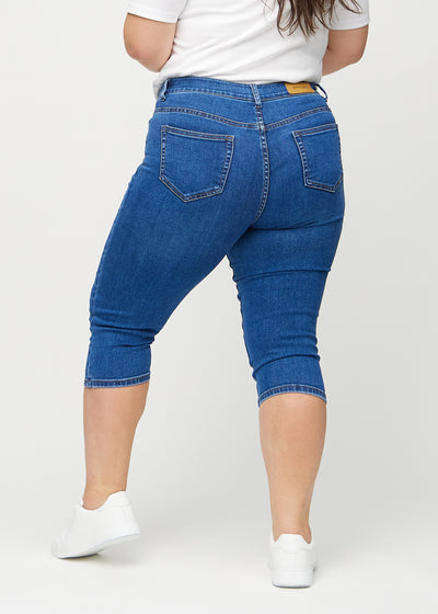 Mørk denim skinny capris set bagfra på en plus-size model, så man kan se hele produktet.