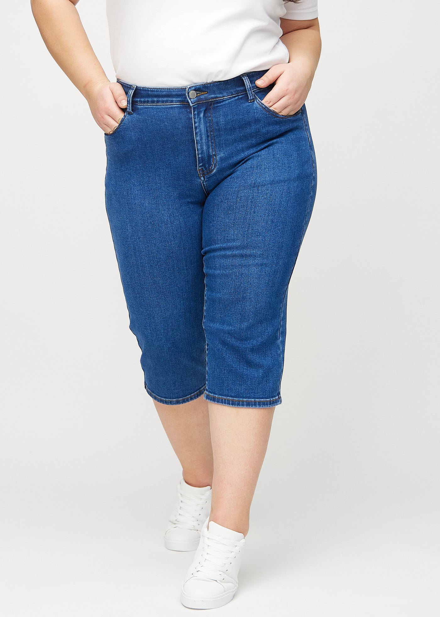 Mørk denim regular capris, modelnavn Oceans, som sidder lige til benet og slutter lige under knæet på en plus-size model, set forfra.