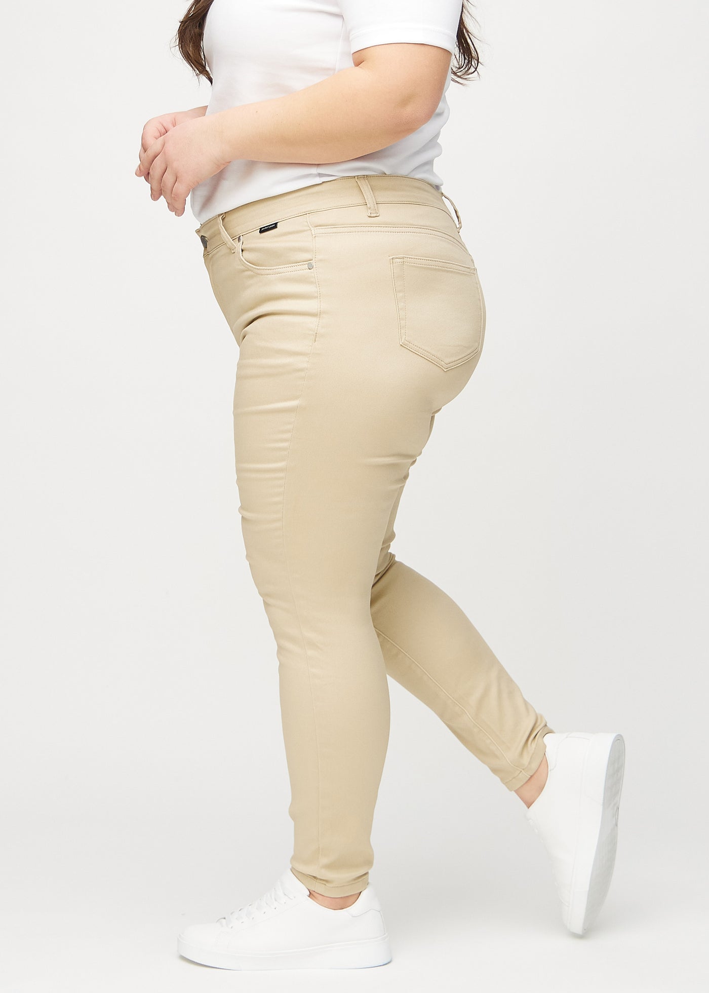 Beige skinny jeans set fra siden på en plus-size model.