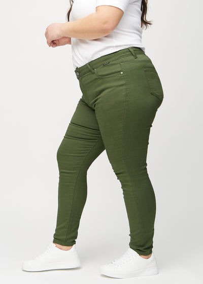 Mørkegrønne skinny jeans set fra siden på en plus-size model.