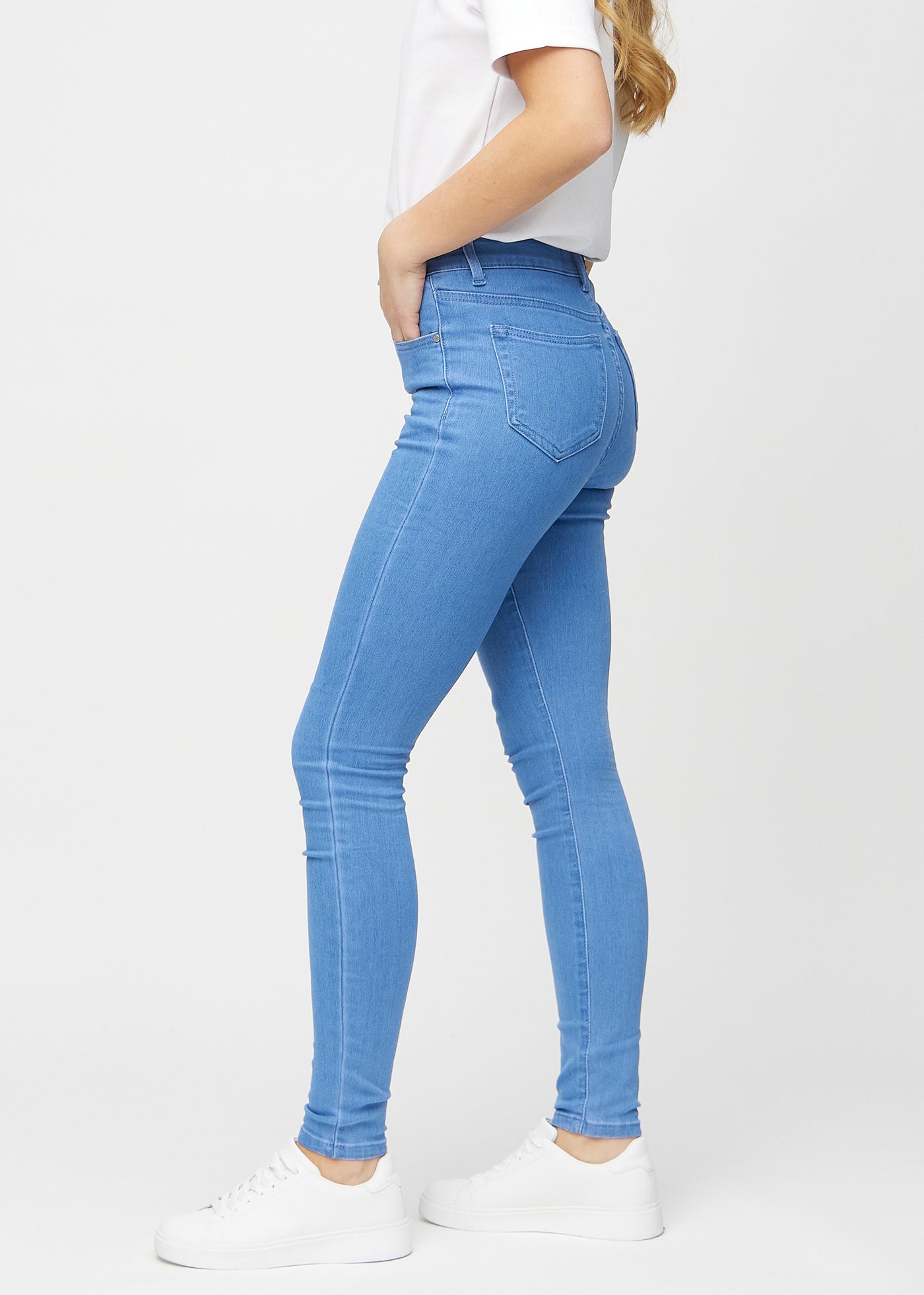 Blå skinny jeans set fra siden på model.