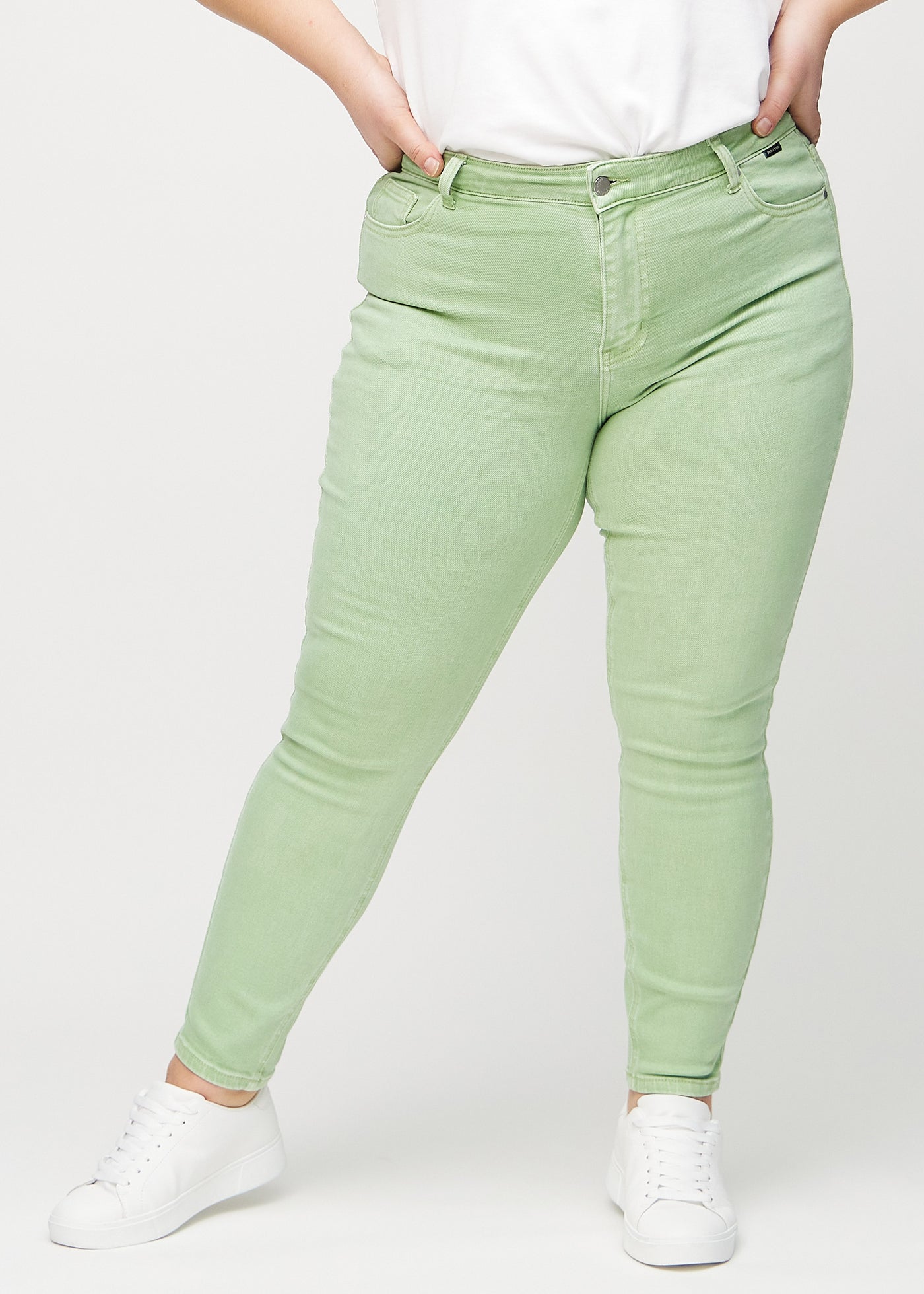 Lysegrønne skinny jeans, modelnavn Mints, som sidder tæt til benet på en plus-size model, set forfra.