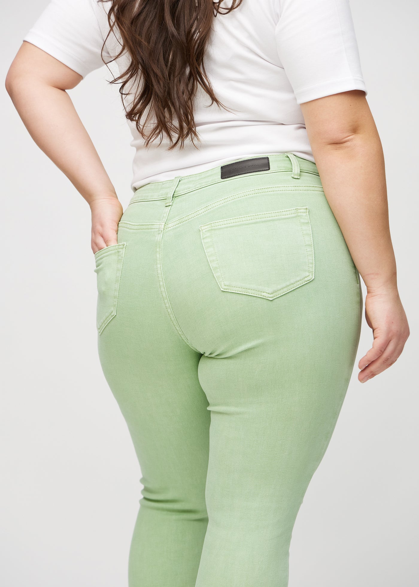 Lysegrønne skinny jeans set bagfra tæt på en plus-size model for at vise detaljer.