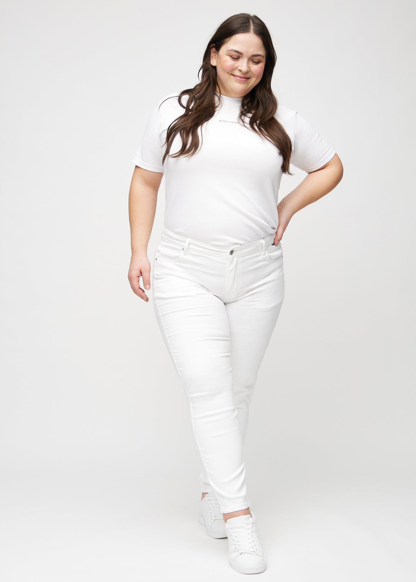 Fuldt billede af en plus-size model i hvide slim jeans.