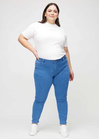 Fuldt billede af en plus-size model i blå slim jeans.