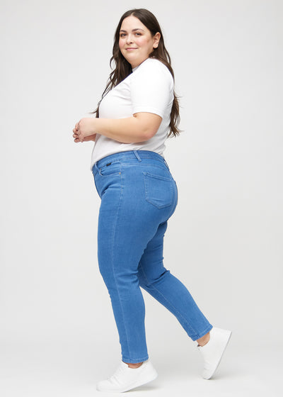 Blå slim jeans set fra siden på en plus-size model.