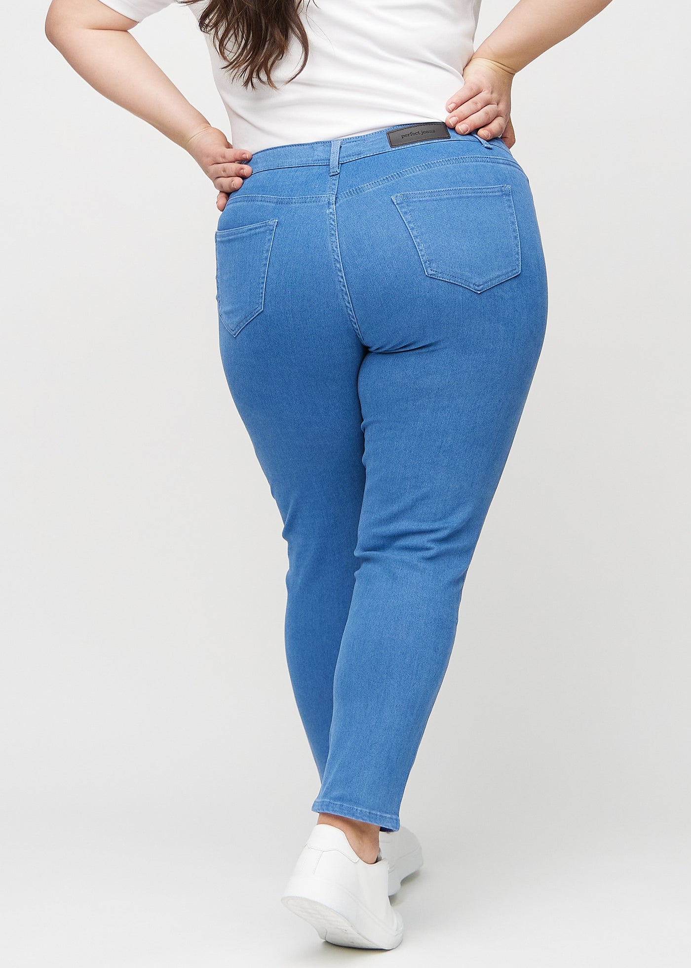  Blå slim jeans set bagfra på en plus-size model, så man kan se hele produktet.