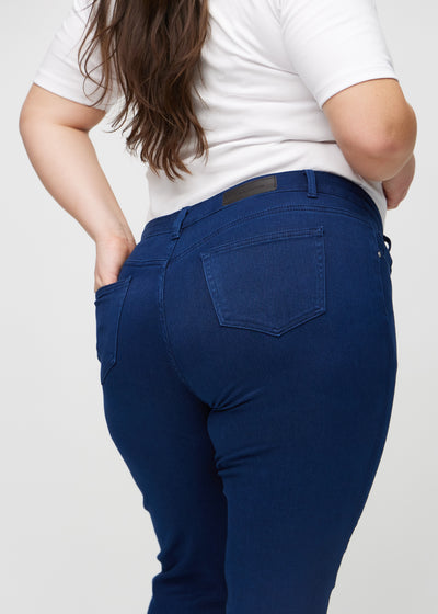 Mørkeblå slim jeans set bagfra tæt på en plus-size model for at vise detaljer.