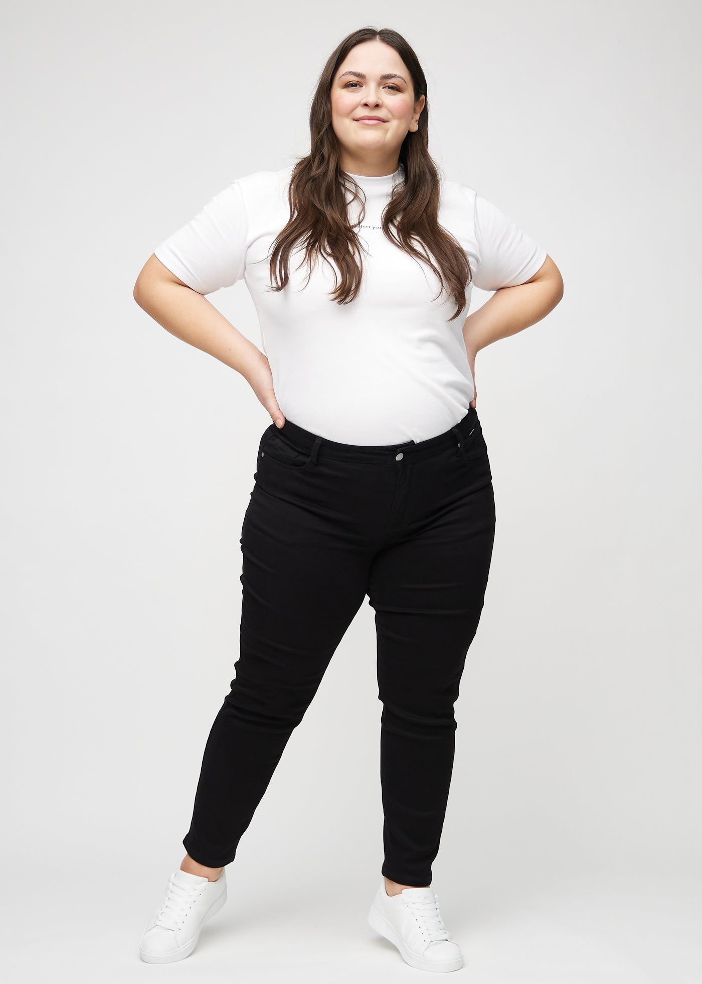 Fuldt billede af en plus-size model i sorte slim jeans.