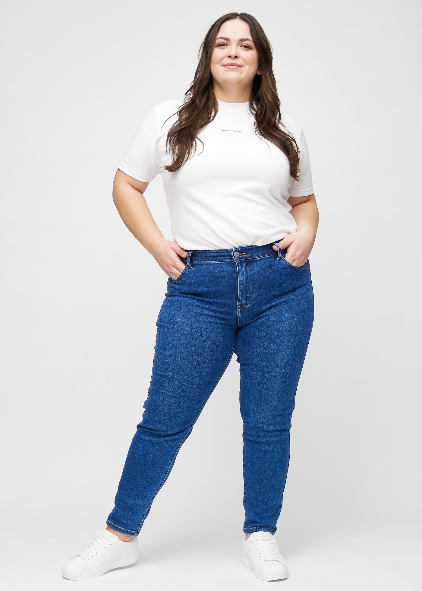 Fuldt billede af en plus-size model i mørk denim slim jeans.