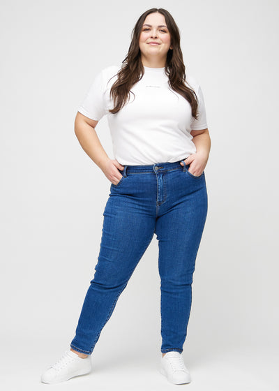 Fuldt billede af en plus-size model i mørk denim slim jeans.