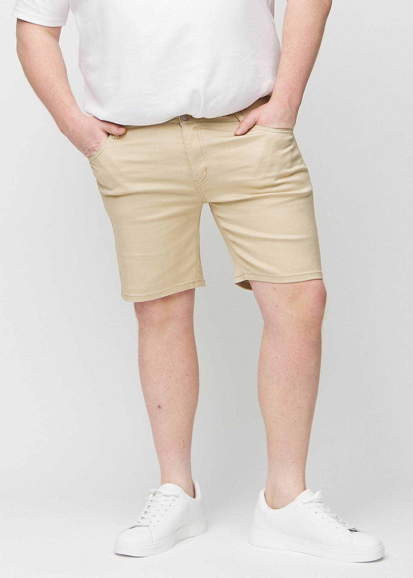 Beige regular middle shorts, som sidder lige langs låret og slutter lige over knæet på en plus-size model, set forfra.