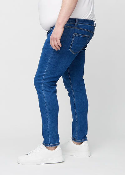 Mørk denim slim jeans set fra siden på en plus-size model.