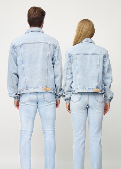 Unisex lyseblå denim jakke set bagfra på mand og kvinde, viser rygdetaljer og højkvalitetssømme.
