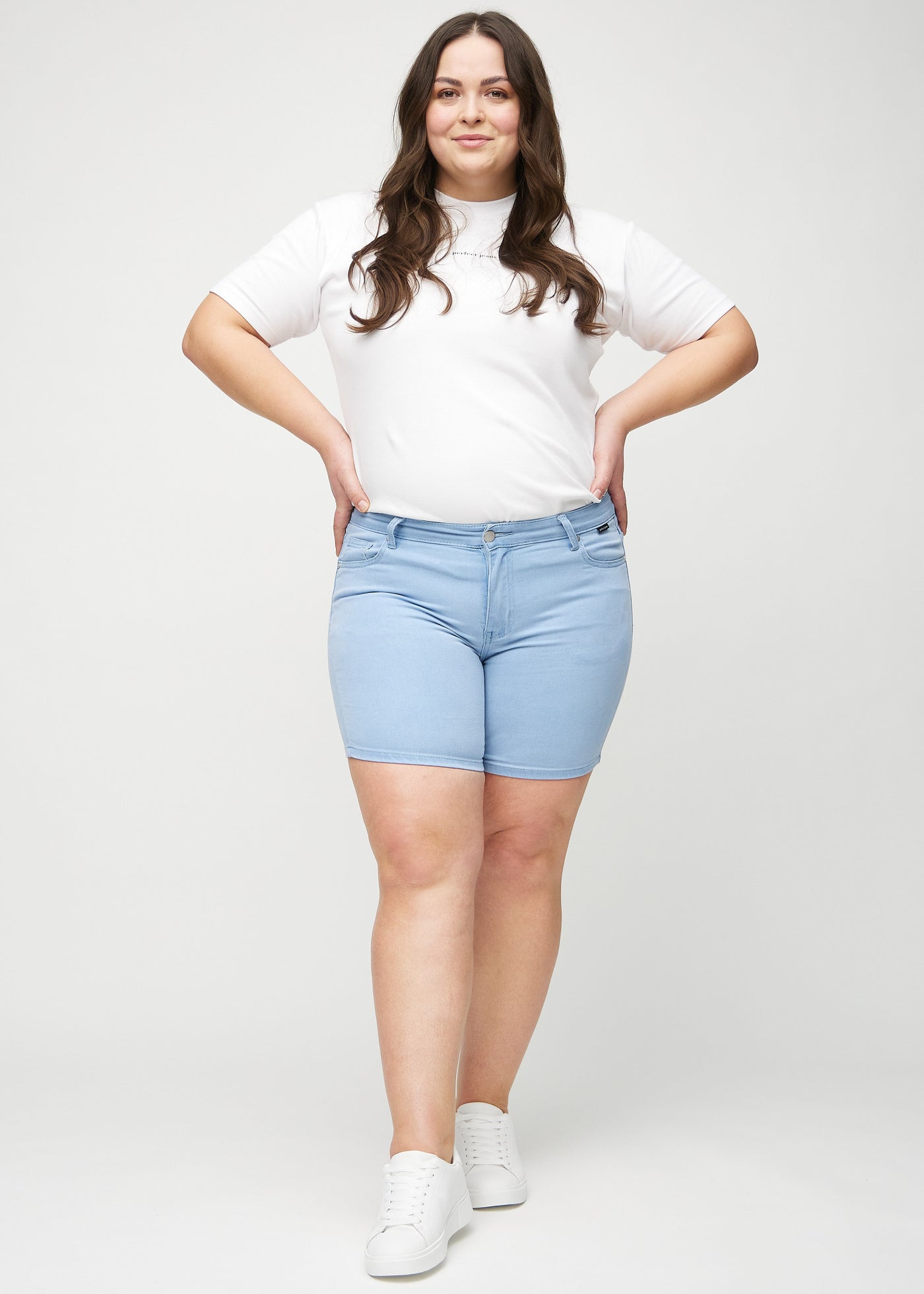 Plus-size model går ind i billedet, strækker i sine shorts, viser dem frem ved at dreje rundt, og forlader derefter billedet.