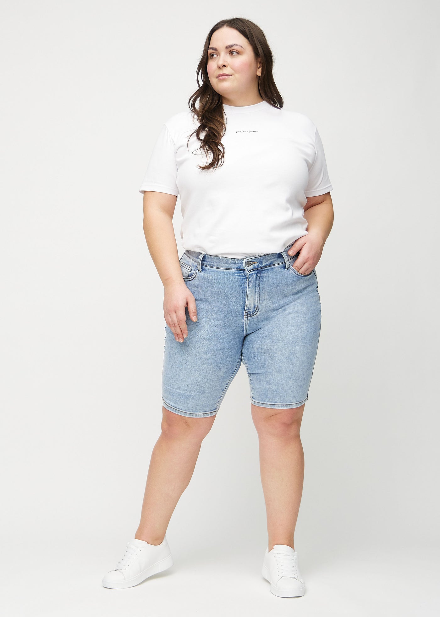 Plus-size model går ind i billedet, strækker i sine shorts, viser dem frem ved at dreje rundt, og forlader derefter billedet.