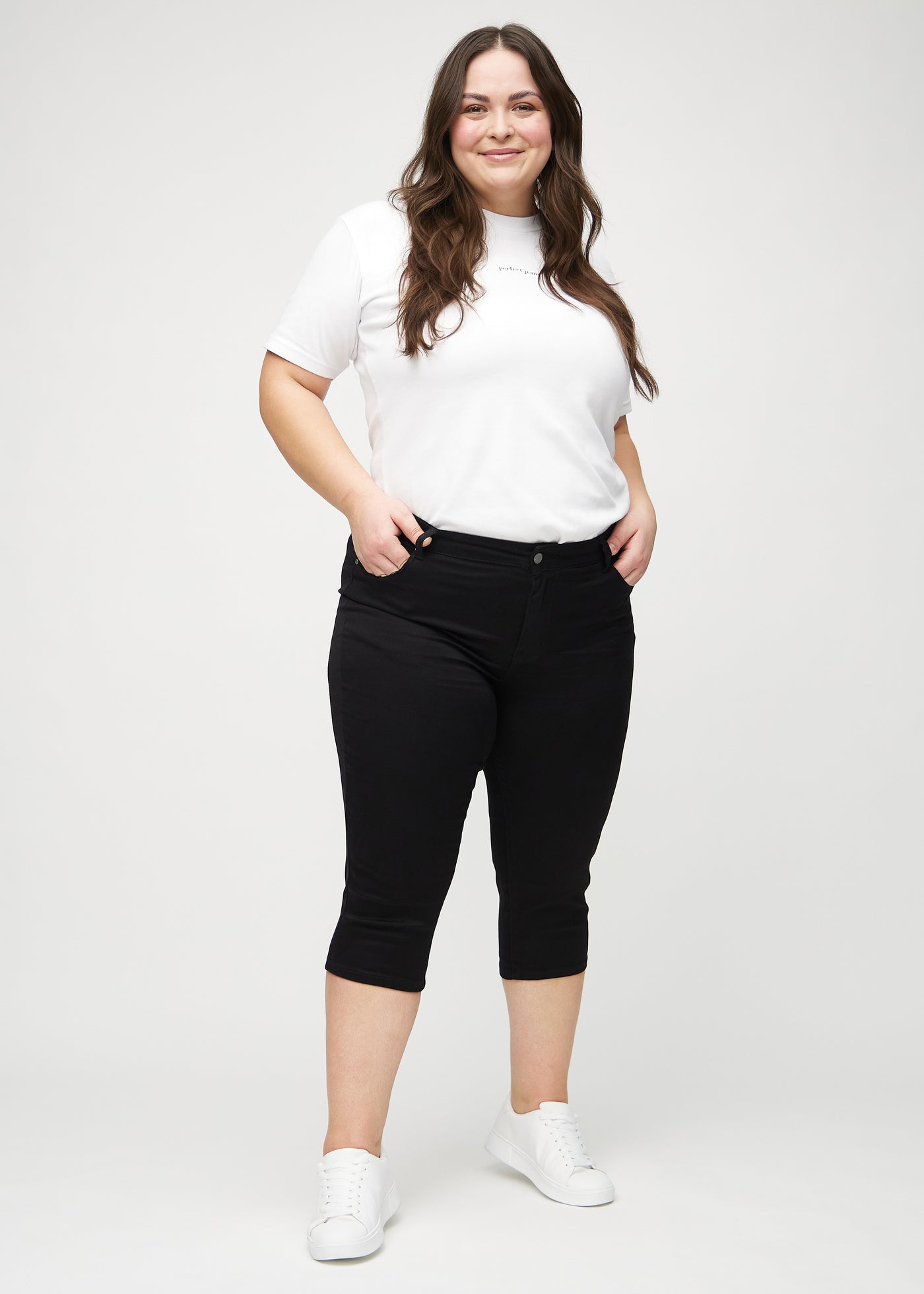 Plus-size model går ind i billedet, strækker i sine capris, viser dem frem ved at dreje rundt, og forlader derefter billedet.