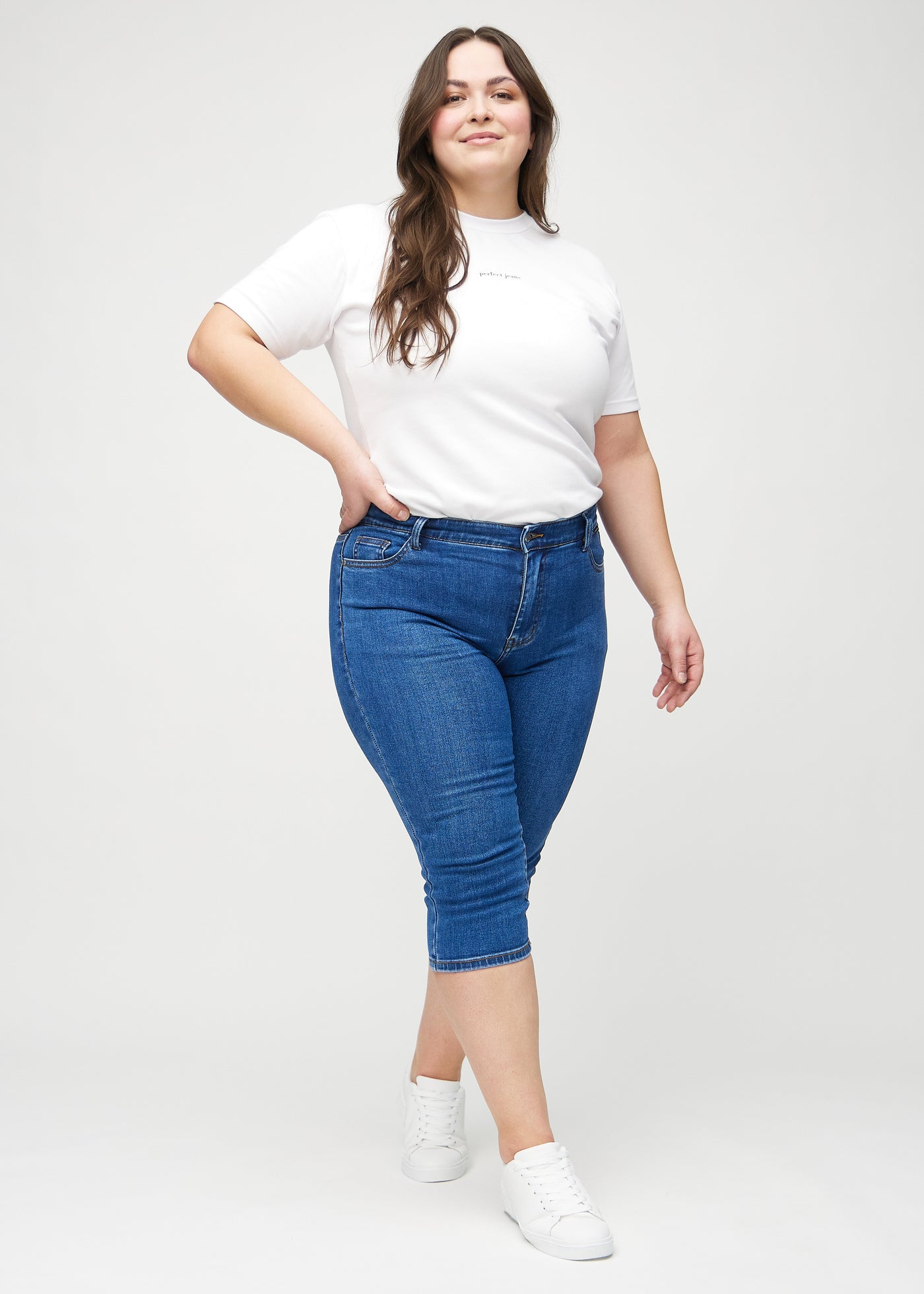 Plus-size model går ind i billedet, strækker i sine capris, viser dem frem ved at dreje rundt, og forlader derefter billedet.