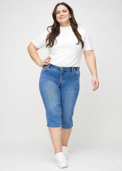 Plus-size model går ind i billedet, strækker i sine capris, viser dem frem ved at dreje rundt, og forlader derefter billedet.