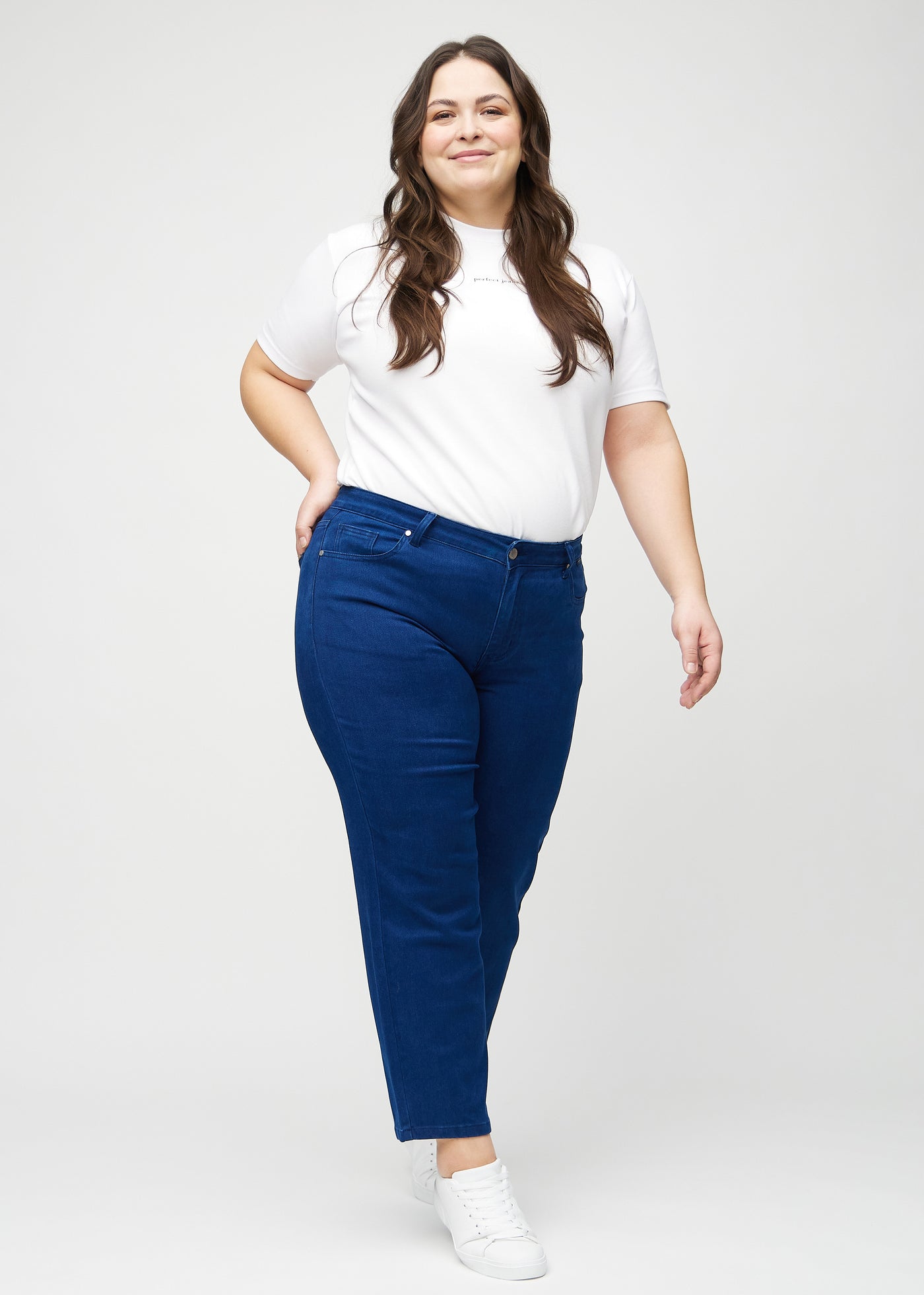 Plus-size model går ind i billedet, strækker i jeansene, viser dem frem ved at dreje rundt, og forlader derefter billedet.