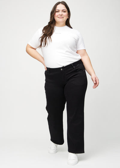 Plus-size model går ind i billedet, strækker i jeansene, viser dem frem ved at dreje rundt, og forlader derefter billedet.