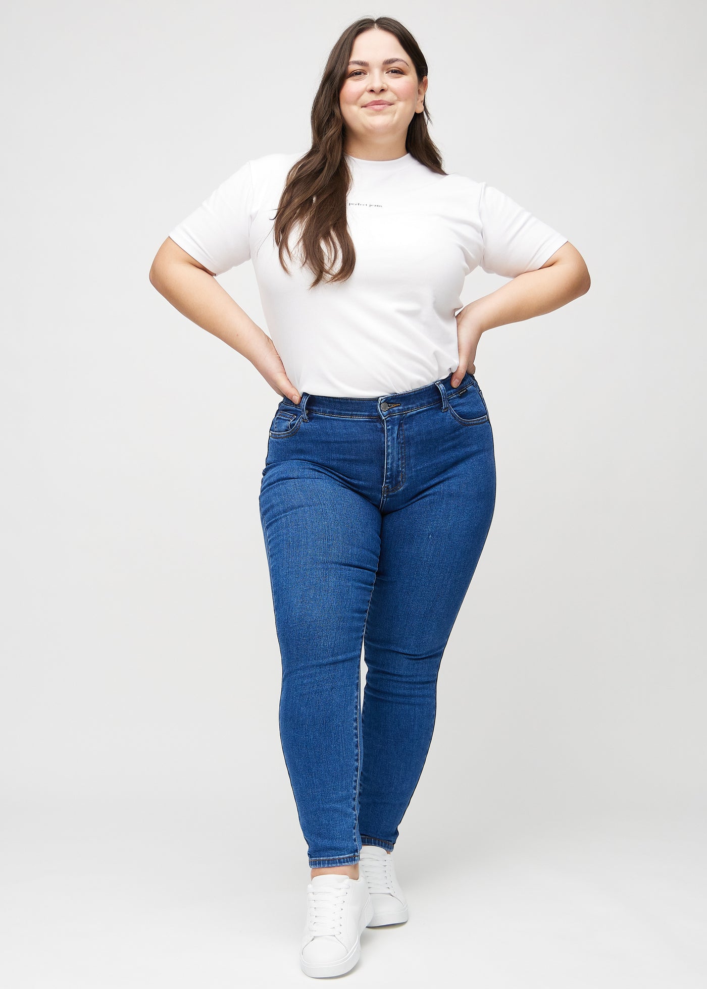 Plus-size model går ind i billedet, strækker i jeansene, viser dem frem ved at dreje rundt, og forlader derefter billedet.